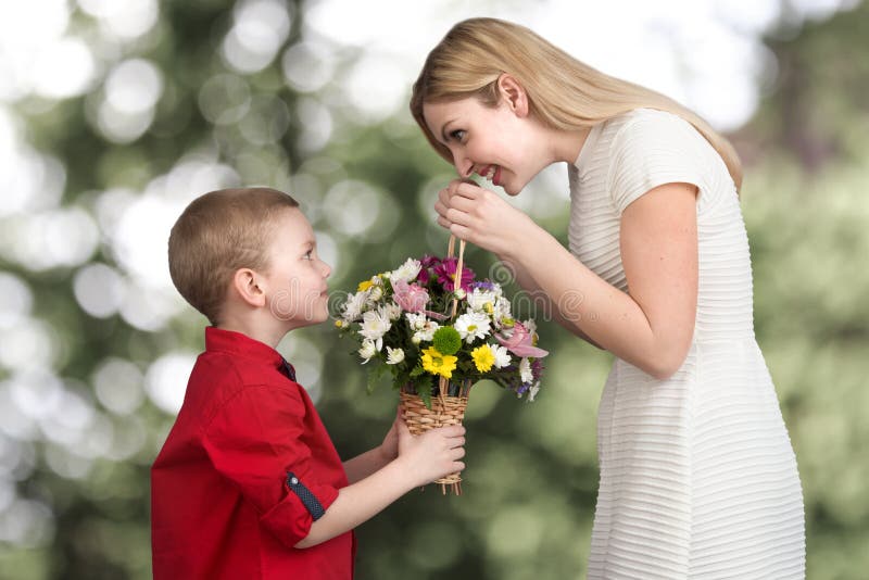 Mãe bonita nova com seu filho Uma mulher e um bebê com um ramalhete, uma cesta das flores Conceito da mola das férias em família imagens de stock royalty free Mãe bonita nova com seu filho Uma mulher e um bebê com um ramalhete, uma cesta das flores Conceito da mola das férias em família imagens de stock royalty free