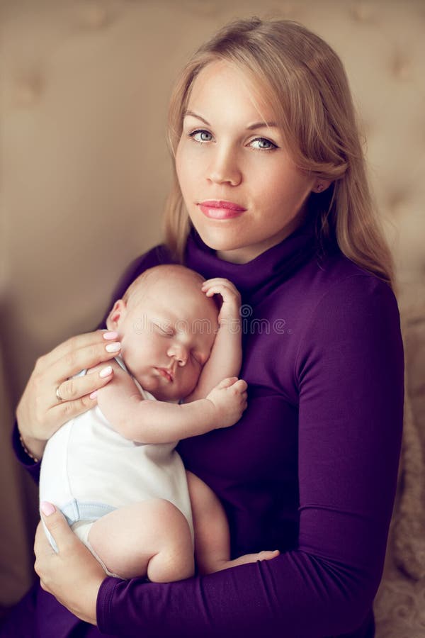 Mãe bonita nova que guarda o bebê recém-nascido de sono nas mãos dentro imagens de stock Mãe bonita nova que guarda o bebê recém-nascido de sono nas mãos dentro imagens de stock