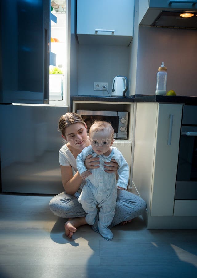 Mãe bonita que senta-se com seu filho do bebê no assoalho da cozinha em l fotos de stock Mãe bonita que senta-se com seu filho do bebê no assoalho da cozinha em l fotos de stock