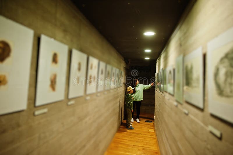 Mãe com filhos a explorar exposições em salas de museu fotos de stock