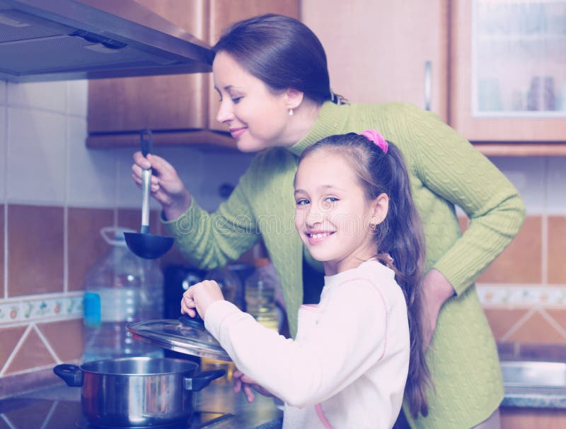 Mãe com a filha que cozinha na cozinha imagens de stock royalty free Mãe com a filha que cozinha na cozinha imagens de stock royalty free