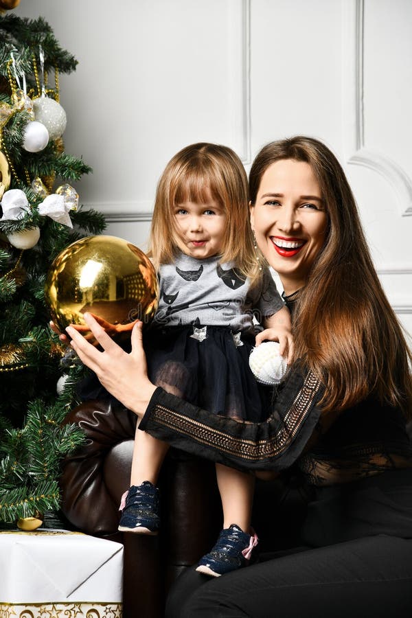 Mãe com sua filha da criança que comemora perto da árvore de Natal fotografia de stock Mãe com sua filha da criança que comemora perto da árvore de Natal fotografia de stock