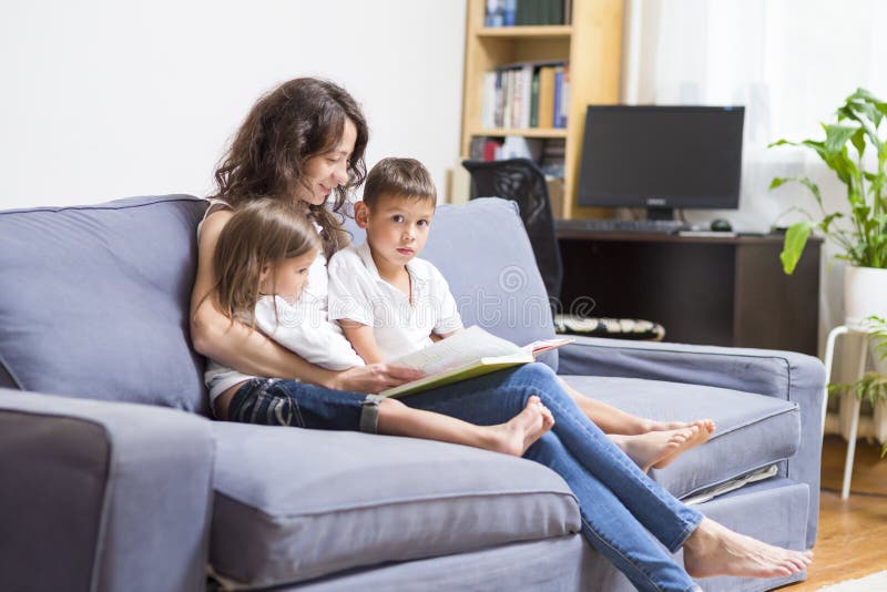 Mãe com suas duas crianças que leem um livro junto fotos de stock Mãe com suas duas crianças que leem um livro junto fotos de stock
