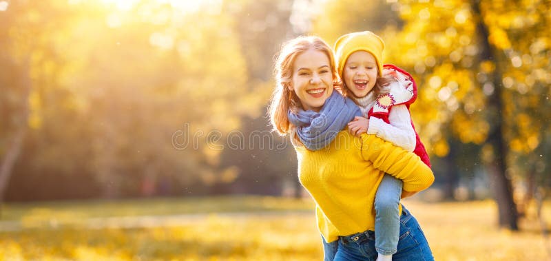 A mãe da família e a filha felizes da criança no outono andam