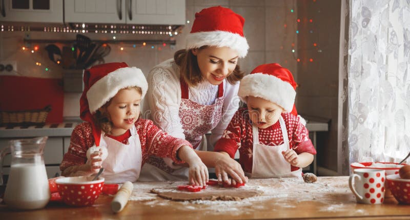 A mãe e as crianças felizes da família cozem cookies para o Natal fotos de stock