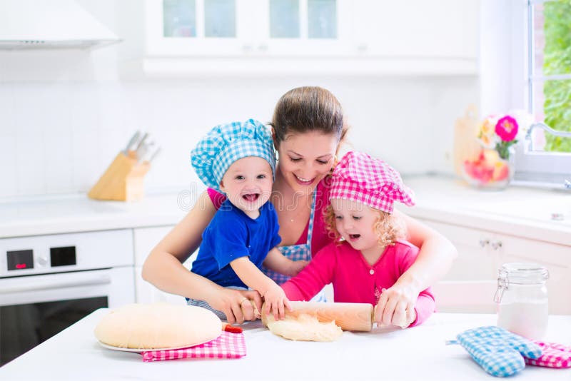 Mãe e crianças que cozem uma torta