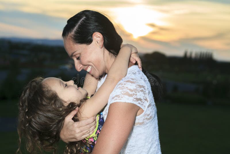 A mãe e a filha bonitas no por do sol expõem ao sol feixes fotografia de stock A mãe e a filha bonitas no por do sol expõem ao sol feixes fotografia de stock