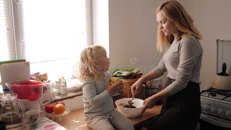 Mãe e filha misturam o batedor de biscoitos na cozinha