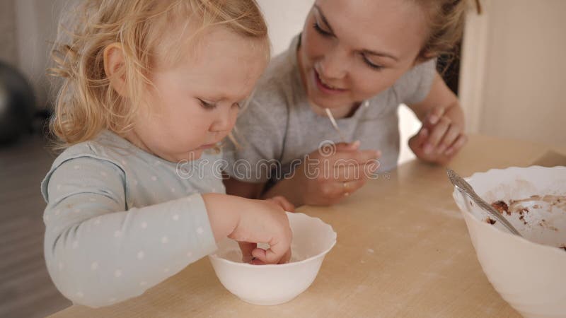 Mãe e filha pequena conversando na mesa da cozinha enquanto cozinhavam