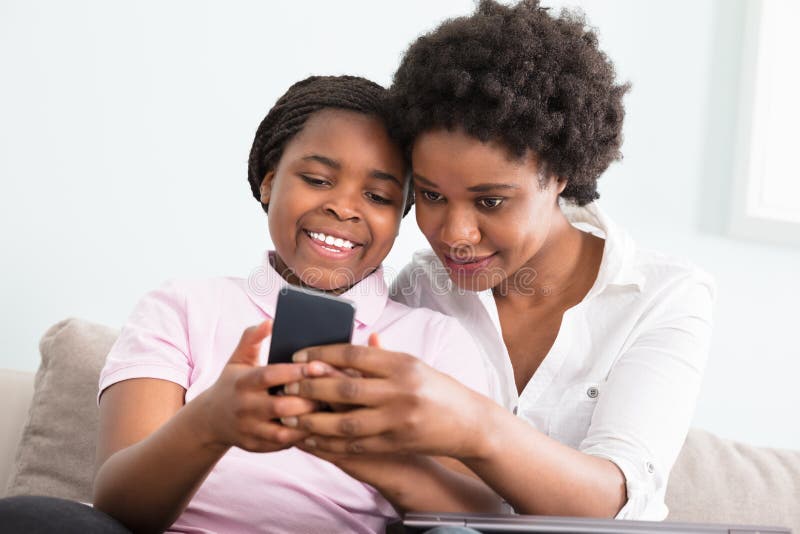 Mãe e filha que olham o telefone esperto foto de stock Mãe e filha que olham o telefone esperto foto de stock