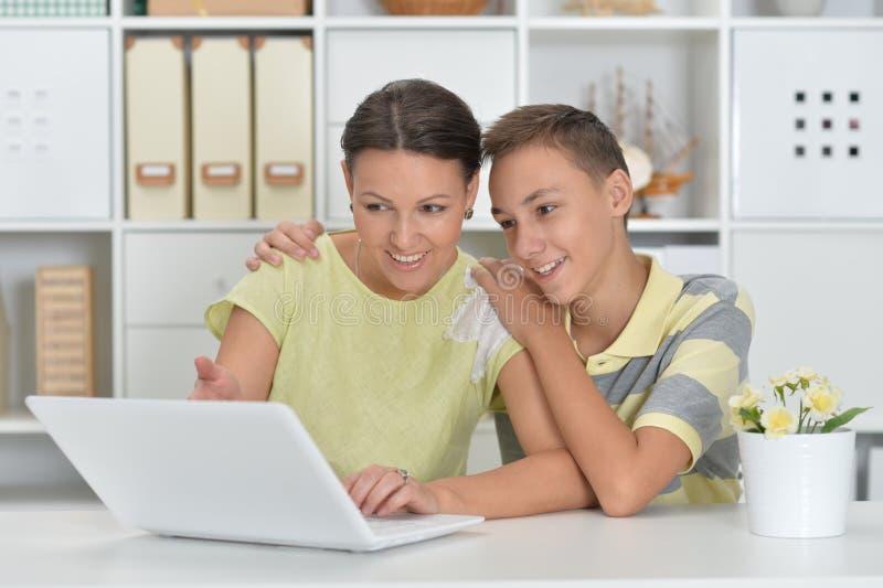 Mãe e filho usando o laptop moderno à mesa imagens de stock