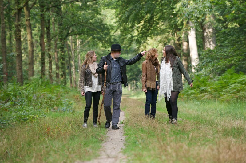 Mãe e pai que andam com as filhas na floresta fotografia de stock
