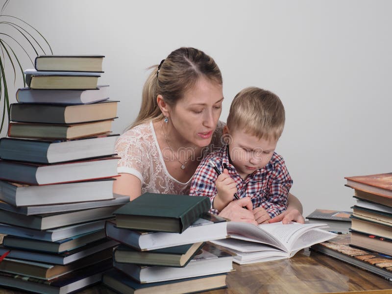 A mãe ensina o filho ler entre as pilhas de livros imagens de stock royalty free A mãe ensina o filho ler entre as pilhas de livros imagens de stock royalty free