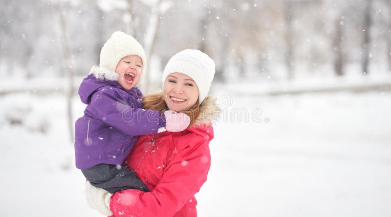 Mãe feliz da família e filha do bebê que joga e que ri na neve do inverno fotografia de stock royalty free Mãe feliz da família e filha do bebê que joga e que ri na neve do inverno fotografia de stock royalty free