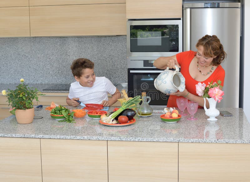 Mãe feliz e filho que preparam o almoço O filho olha sua mãe fotos de stock Mãe feliz e filho que preparam o almoço O filho olha sua mãe fotos de stock