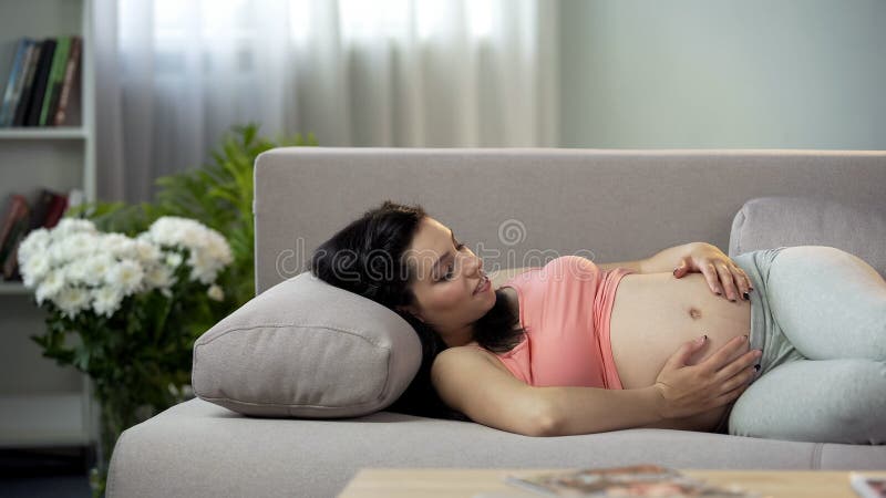 Mãe futura nova que afaga sua barriga e que comunica-se com a vinda recém-nascida foto de stock royalty free Mãe futura nova que afaga sua barriga e que comunica-se com a vinda recém-nascida foto de stock royalty free