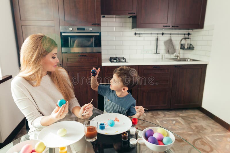 Mãe nova da Páscoa feliz e seus ovos da páscoa de pintura do filho pequeno foto de stock Mãe nova da Páscoa feliz e seus ovos da páscoa de pintura do filho pequeno foto de stock