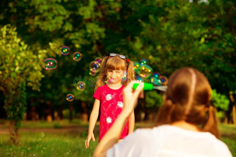 Mãe nova e filha pequena que jogam no parque com bolhas de sabão Família do amor, infância fotos de stock Mãe nova e filha pequena que jogam no parque com bolhas de sabão Família do amor, infância fotos de stock