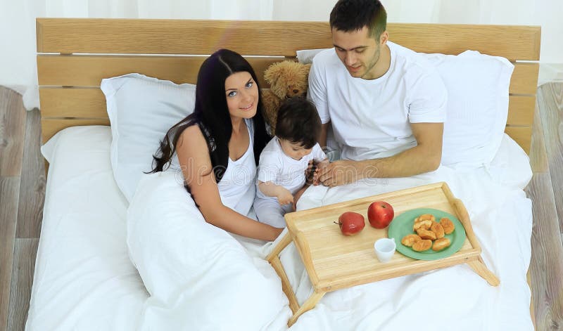Mãe, pai, bebê na cama na sala fotos de stock Mãe, pai, bebê na cama na sala fotos de stock