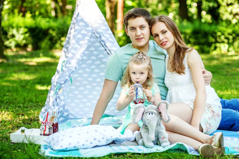 Mãe, pai e filha pequena em um piquenique O conceito de f imagens de stock royalty free Mãe, pai e filha pequena em um piquenique O conceito de f imagens de stock royalty free