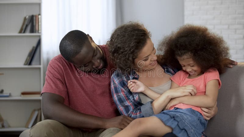 Mãe que agrada e que diverte sua filha pequena, família feliz que senta-se no sofá fotos de stock Mãe que agrada e que diverte sua filha pequena, família feliz que senta-se no sofá fotos de stock