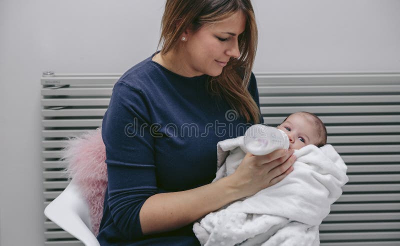 Mãe que dá a garrafa a ela recém-nascida fotos de stock Mãe que dá a garrafa a ela recém-nascida fotos de stock