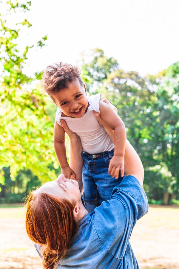 Mãe que lanç acima do filho para o divertimento exterior no dia ensolarado fotos de stock Mãe que lanç acima do filho para o divertimento exterior no dia ensolarado fotos de stock