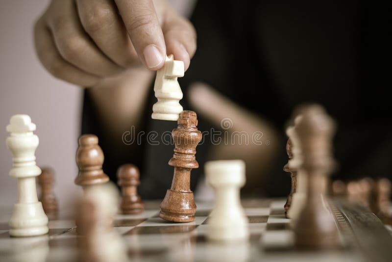 Mão ascendente próxima do tiro da mulher de negócio que joga a placa de xadrez para ganhar matando o rei da competição oponente d fotos de stock Mão ascendente próxima do tiro da mulher de negócio que joga a placa de xadrez para ganhar matando o rei da competição oponente d fotos de stock