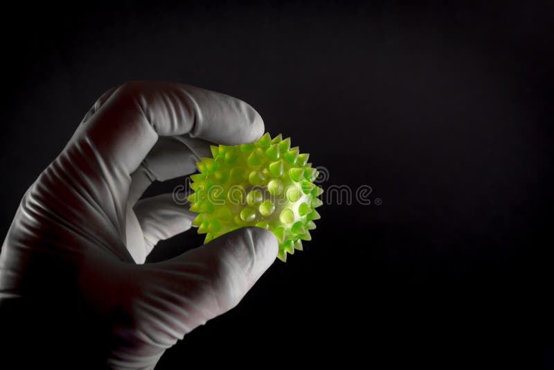 Medical hand in latex holding a large green virus shape with copyspace room. Medical hand in latex holding a large green virus shape with copyspace room