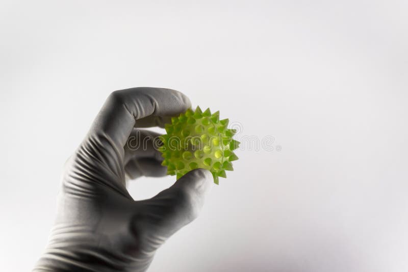 Medical hand in latex holding a large green virus shape with copyspace room. Medical hand in latex holding a large green virus shape with copyspace room