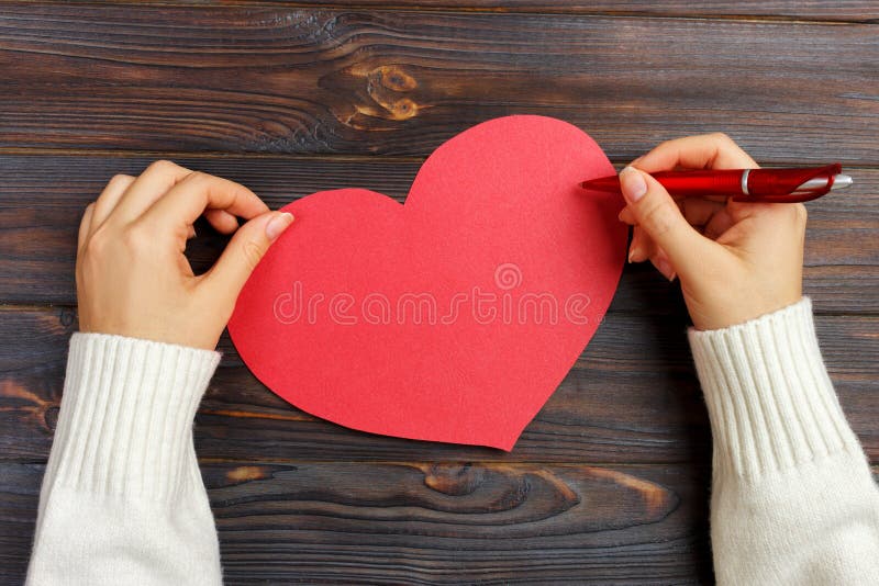 Mão da carta de amor da escrita da menina em Valentine Day Cartão vermelho feito a mão do coração A mulher escreve no cartão para