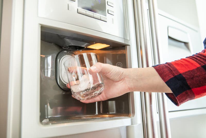 A mão da mulher guarda o vidro e usa o refrigerador