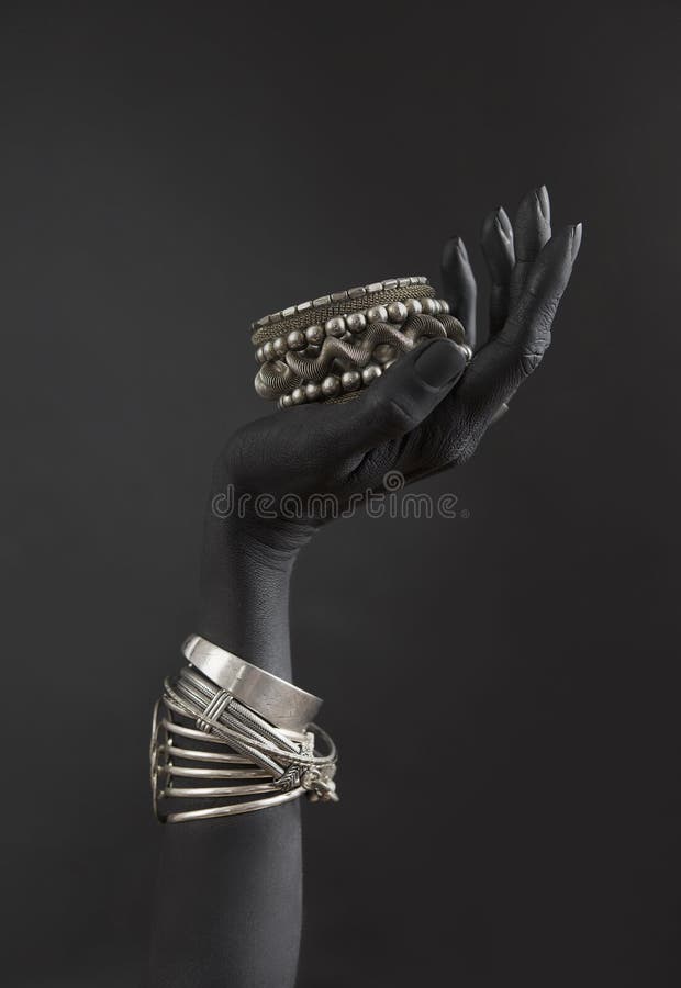 A mão da mulher negra com joia de prata Braceletes orientais em uma mão pintada preta Jóia de prata imagens de stock royalty free