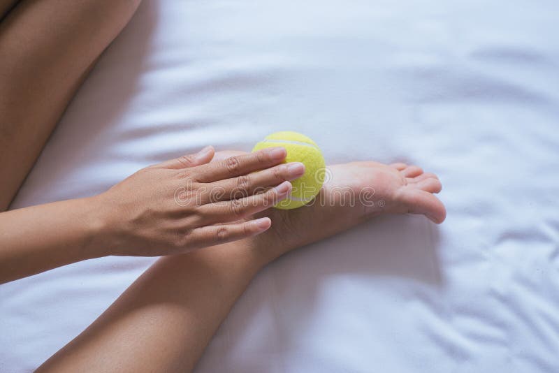 A mão da mulher que dá a massagem com a bola de tênis a ela paga no quarto, massagem das solas do pé fotos de stock A mão da mulher que dá a massagem com a bola de tênis a ela paga no quarto, massagem das solas do pé fotos de stock