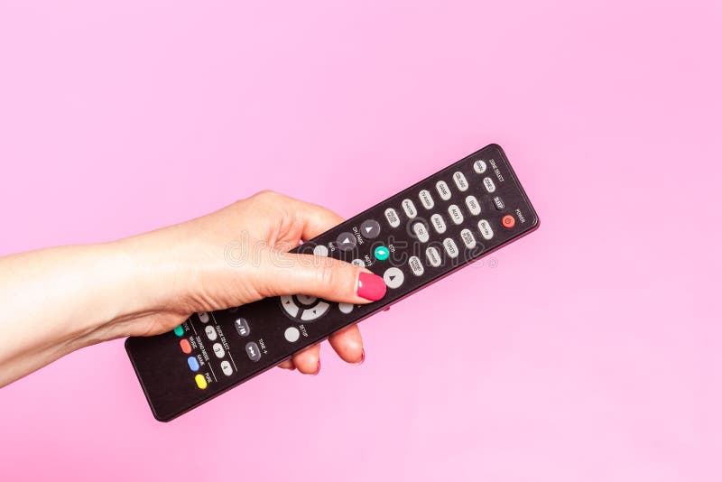 Mão da mulher que guarda o controlo a distância, no fundo cor-de-rosa imagem de stock Mão da mulher que guarda o controlo a distância, no fundo cor-de-rosa imagem de stock