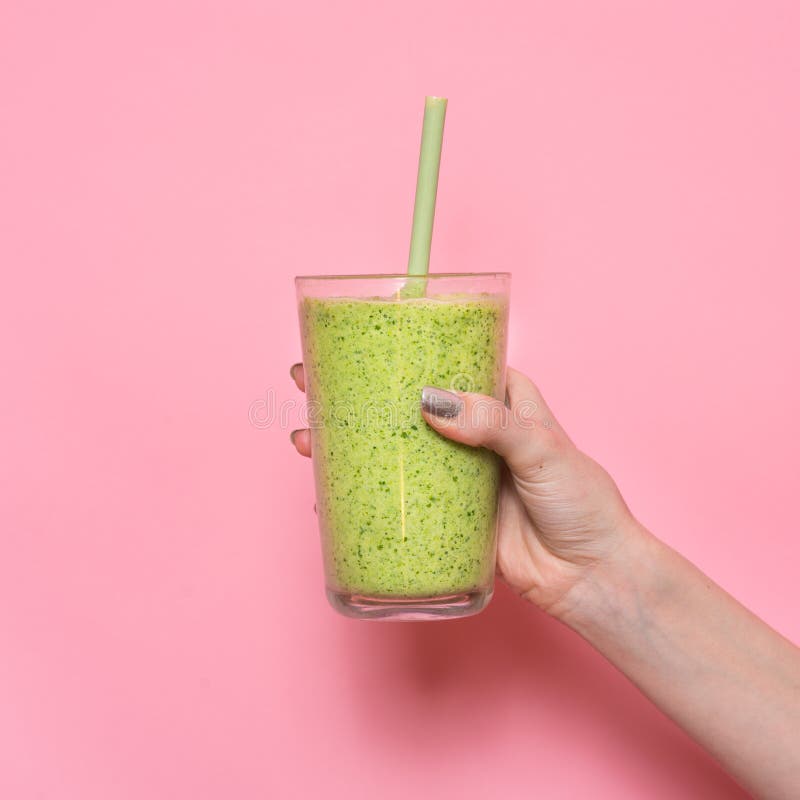 Mão da mulher que mantém a agitação do batido contra a parede cor-de-rosa imagem de stock Mão da mulher que mantém a agitação do batido contra a parede cor-de-rosa imagem de stock