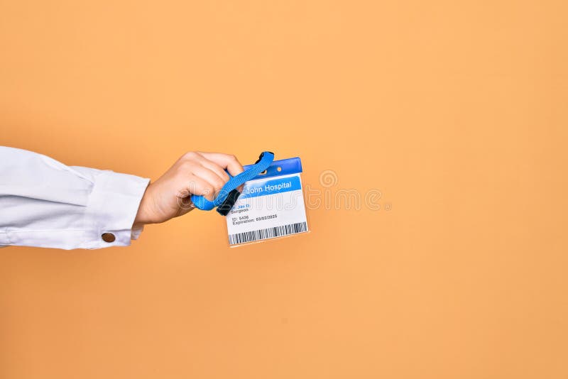 Mão de uma jovem caucasiana segurando cartão de identificação médico sobre fundo amarelo isolado