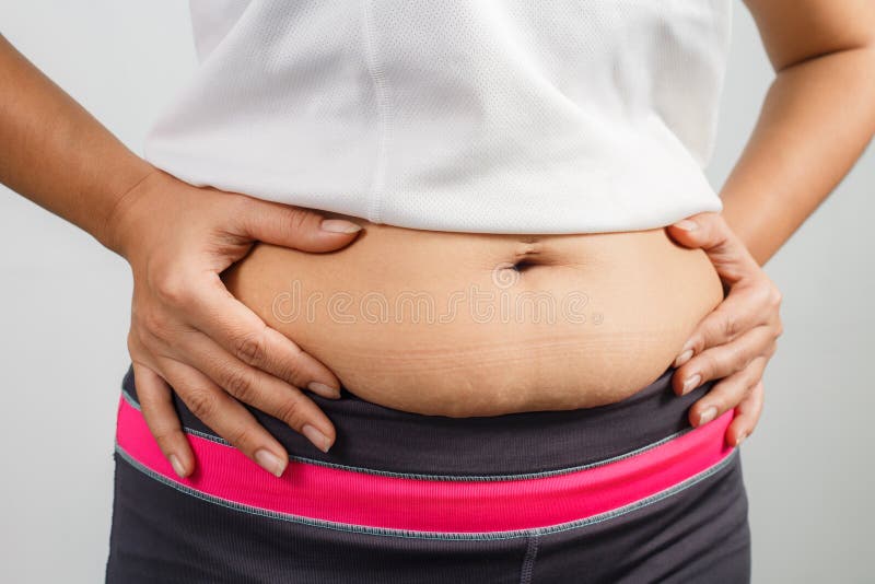 Mão excesso de peso da mulher que comprime a barriga excessiva gorda
