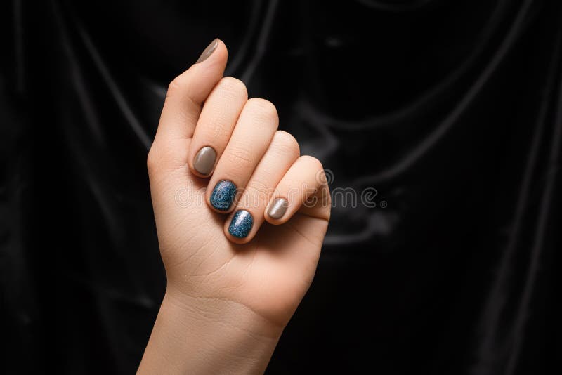 Mão feminina com desenho de unhas de galáxia. manicure azul esmalte. mão da mulher sobre o fundo do tecido negro