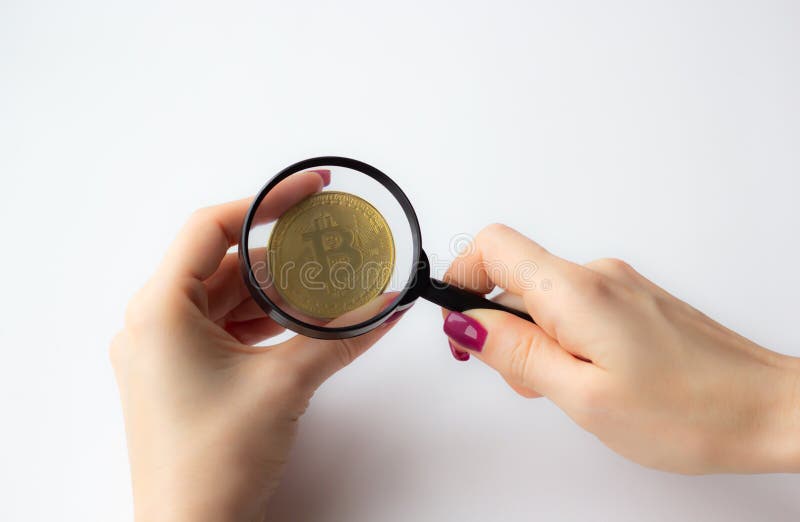 Mão fêmea que guarda uma lupa com a moeda dourada do bitcoin no fundo branco fotografia de stock royalty free Mão fêmea que guarda uma lupa com a moeda dourada do bitcoin no fundo branco fotografia de stock royalty free