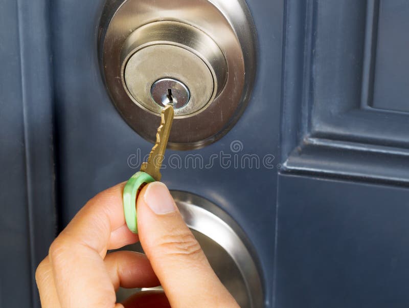 Mão fêmea que põe a chave da casa na fechadura da porta