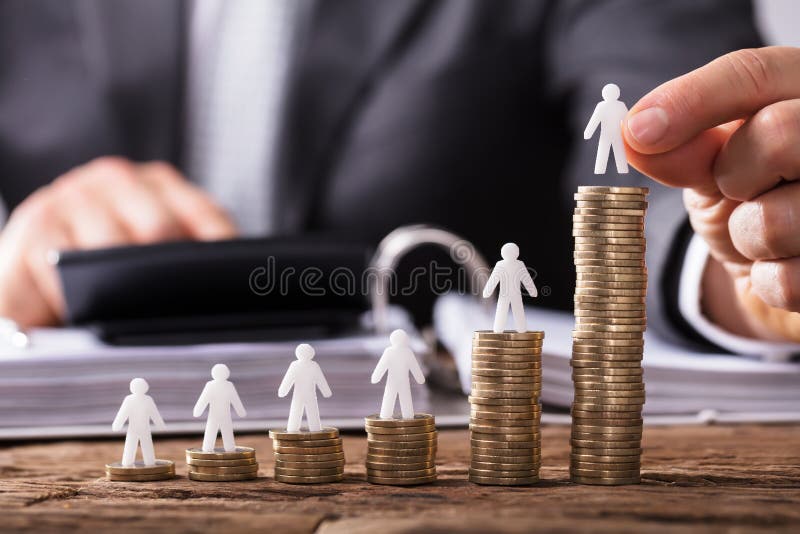 Mão humana que coloca a figura humana em aumentar moedas empilhadas fotografia de stock Mão humana que coloca a figura humana em aumentar moedas empilhadas fotografia de stock