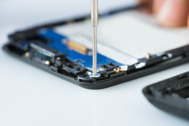 Mão humana que repara o telefone celular com chave de fenda fotografia de stock Mão humana que repara o telefone celular com chave de fenda fotografia de stock