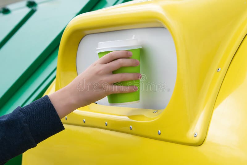 A mão joga o copo de papel em um tanque amarelo do lixo, close-up fotos de stock A mão joga o copo de papel em um tanque amarelo do lixo, close-up fotos de stock