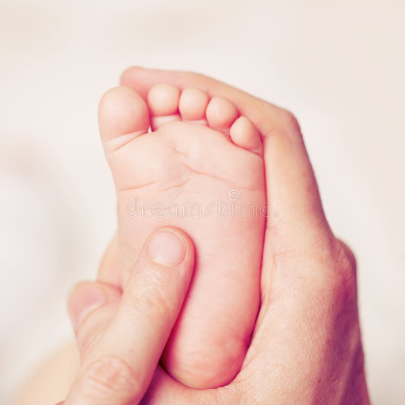 Mão masculina com pés do bebê