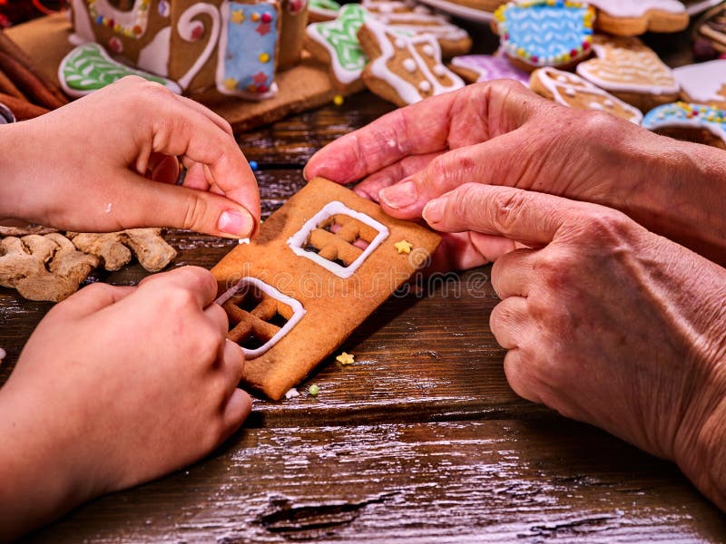 Mão que cozinha a casa de pão-de-espécie do Natal foto de stock