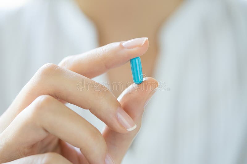 Mão que guarda o comprimido azul da cápsula foto de stock Mão que guarda o comprimido azul da cápsula foto de stock