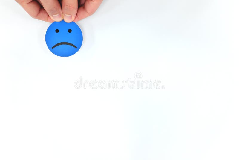 Mão segurando uma emoção azul triste em fundo branco com espaço de cópia. conceito de atendimento ao cliente insatisfeito e mau cl