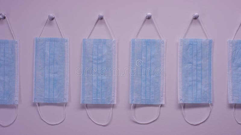 A mão toma a máscara protetora da parede Máscaras cirúrgicas do orelha-laço na parede branca Uma máscara para a proteção contra g fotos de stock A mão toma a máscara protetora da parede Máscaras cirúrgicas do orelha-laço na parede branca Uma máscara para a proteção contra g fotos de stock