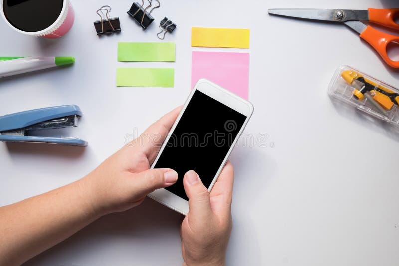Mão usando o smartphone na mesa de escritório fotografia de stock Mão usando o smartphone na mesa de escritório fotografia de stock